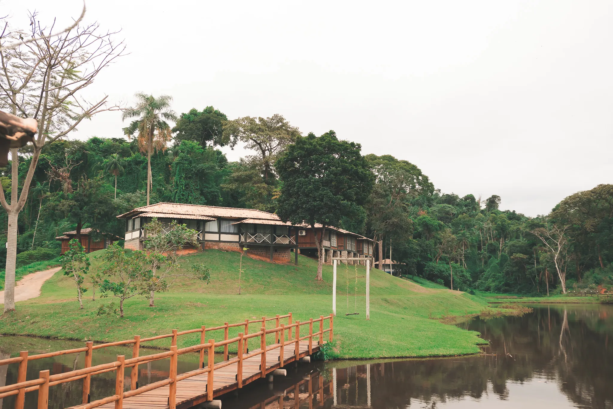Vista panorâmica do Hotel Fazenda Bom Retiro com lago e chalés cercados pela natureza